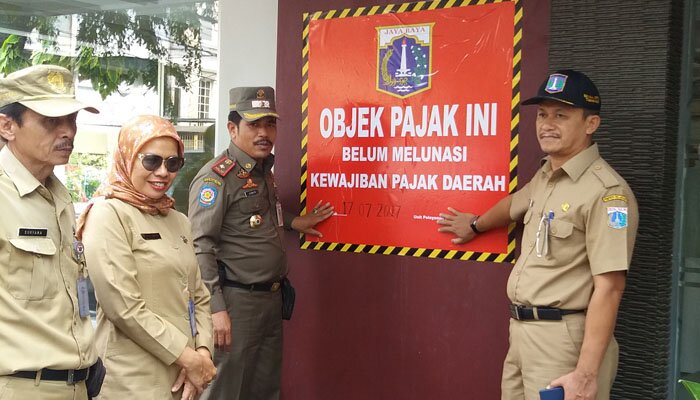 Petugas tengah memasang stiker atau papan belum melunasi kewajiban pajak daerah ke sebuah hotel. (Tarta)