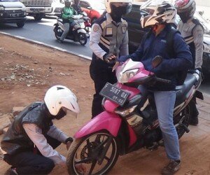 Petugas sedang melakukan pengempesan kendaraan yang sedang parkir di atas trotoar. (wandi)
