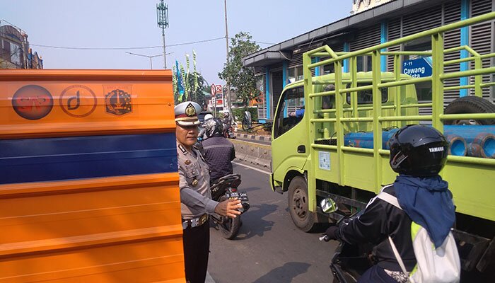 Petugas kepolisian saat tengah mengatur kendaraan yang terjebak macet di Jalan Otista. (Ifand)