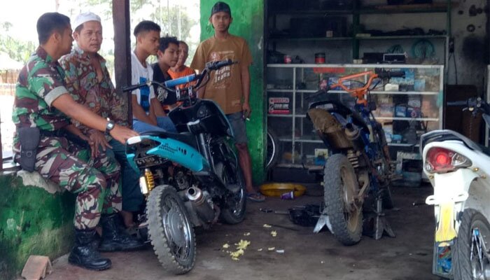 H Cadi pemilik bengkel sedang berbincang dengan Serda Eddy Widodo mengenai kian meningkatnya omzet pasca jalan didesanya leucir usai pelaksanaan TMMD ke 106.(dadan)