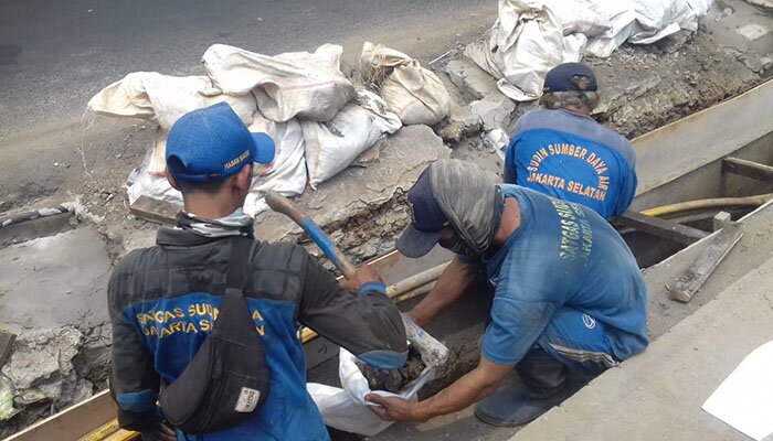 Petugas sedang memperbaiki saluran yang rusak dan penuh lumpur. (wandi)