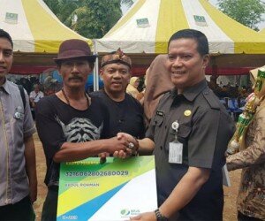 Asda I Kabupaten Bekasi Juadi, menyerahkan secara simbolis kartu kepesertaan pada penggali kubur.(ist)
