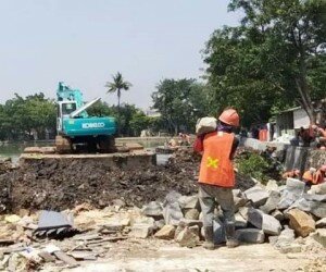 Salah satu alat berat ekskavator tengah mengeruk lumpur di sekitar bangunan rumah warga yang telah dibongkar di pinggir Situ Rawa Besar, kampung Lio, Depok. (anton)