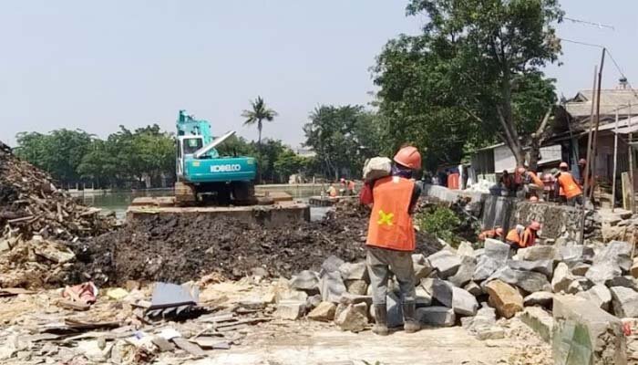 Salah satu alat berat ekskavator tengah mengeruk lumpur di sekitar bangunan rumah warga yang telah dibongkar di pinggir Situ Rawa Besar, kampung Lio, Depok. (anton)