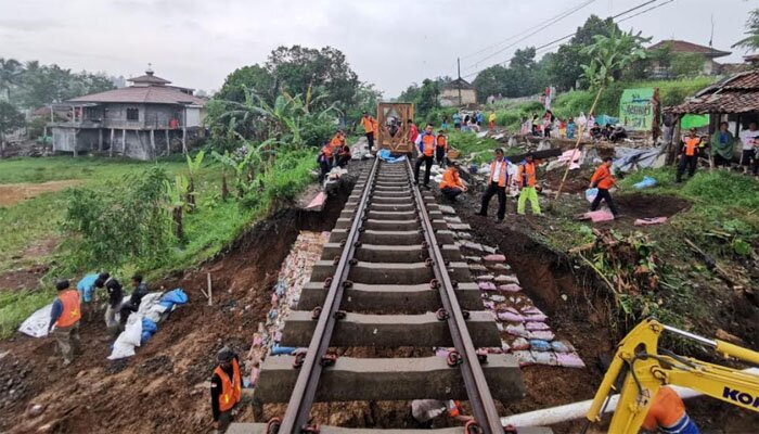 Para pekerja tengah memperbaiki jalur kereta yang terkena dampak longsor. (ist)