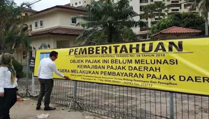 Petugas gabungan memasang spanduk pemberitahuan belum membayar pajak di pagar Hotel Marbella di Jalan Raya Anyer-Cinangka, Desa Bandulu, Kecamatan Anyer. (ist)