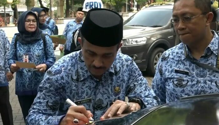 Walikota Jaktim saat menempel stiker penunggak pajak di mobil milik ASN. (Ifand)