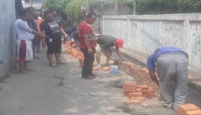 Warga Tugu Selatan, Koja, memperbaiki jalan rusak dengan hasil urunan. (deny)